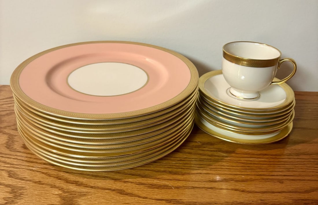 A Collection of Lenox Pink and Gold Acid Etched Encrusted Porcelain Dinnerware: This collection of fine ivory-toned porcelain is manufactured by Lenox and features a wide pink border accented by elaborate acid-etched gold encrusted rims. The decoration consists of a repeating geo
