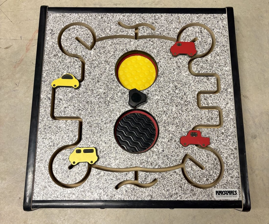Playscapes Inc. Wall Mounted Traffic Themed Sensory Activity Panel: A professional-grade wall-mounted sensory activity panel by Playscapes Inc., specifically designed for commercial children's environments. The square panel features a gray and white speckled terrazzo-