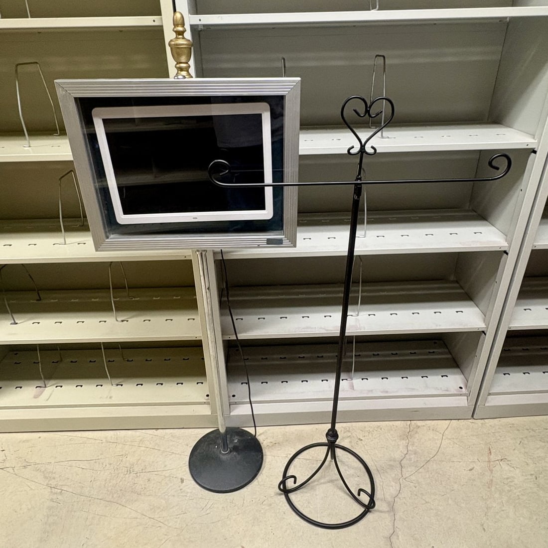 Two Display Stands Including a Framed Digital Media Player on Pedestal and a Wrought Iron Style: FOR PICK UP ONLY (Monday 9/28/26 and Tuesday 9/29/26 ONLY) - CAN NOT SHIP! This lot features two distinct freestanding display solutions intended for commercial or event use. The primary item is a pro