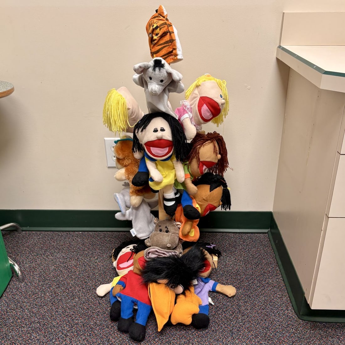 A Collection of Plush Hand Puppets and a Tiered Wooden Display Stand: This lot features a diverse group of approximately fourteen plush hand puppets presented on a tall, tiered wooden display stand. The collection includes a variety of animal-themed puppets, such as a