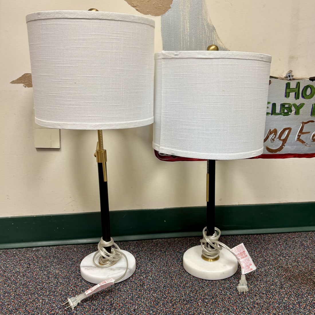 A Pair of Contemporary Adjustable Metal and Marble Table Lamps: A pair of contemporary table lamps featuring an adjustable height design. Each lamp is constructed with a circular white marble base supporting a matte black finished metal shaft with brass-toned