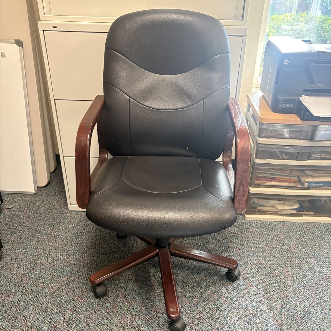 Executive Swivel Office Chair with Mahogany-Finished Wood Frame and Black Upholstery: A traditional-style executive swivel office chair featuring black upholstered seating with contoured horizontal stitching on the backrest and seat. The chair is designed with curved wooden armrests