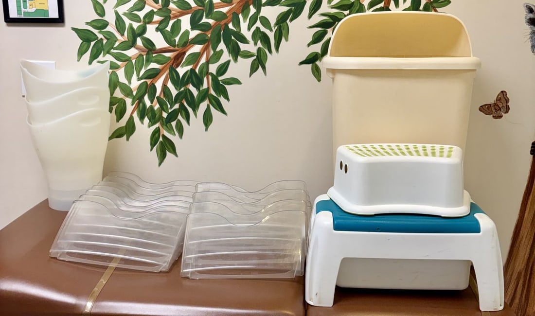 An Assortment of Plastic Nursery and Utility Items including Step Stools and Storage Bins: An assortment of molded plastic utility and organizational items. The group includes one tall, beige utility bin featuring an open, curved top. The collection contains two child-sized step stools: