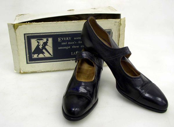 A Pair of Vintage NOS Delta Leather Court Shoes: Of black leather with a single strap and snap closure. Features decorative punching on the toe cap, vamp collar and strap.Circa 1920 - 1940. Labelled size 6. Sold with the original box. This lot forms