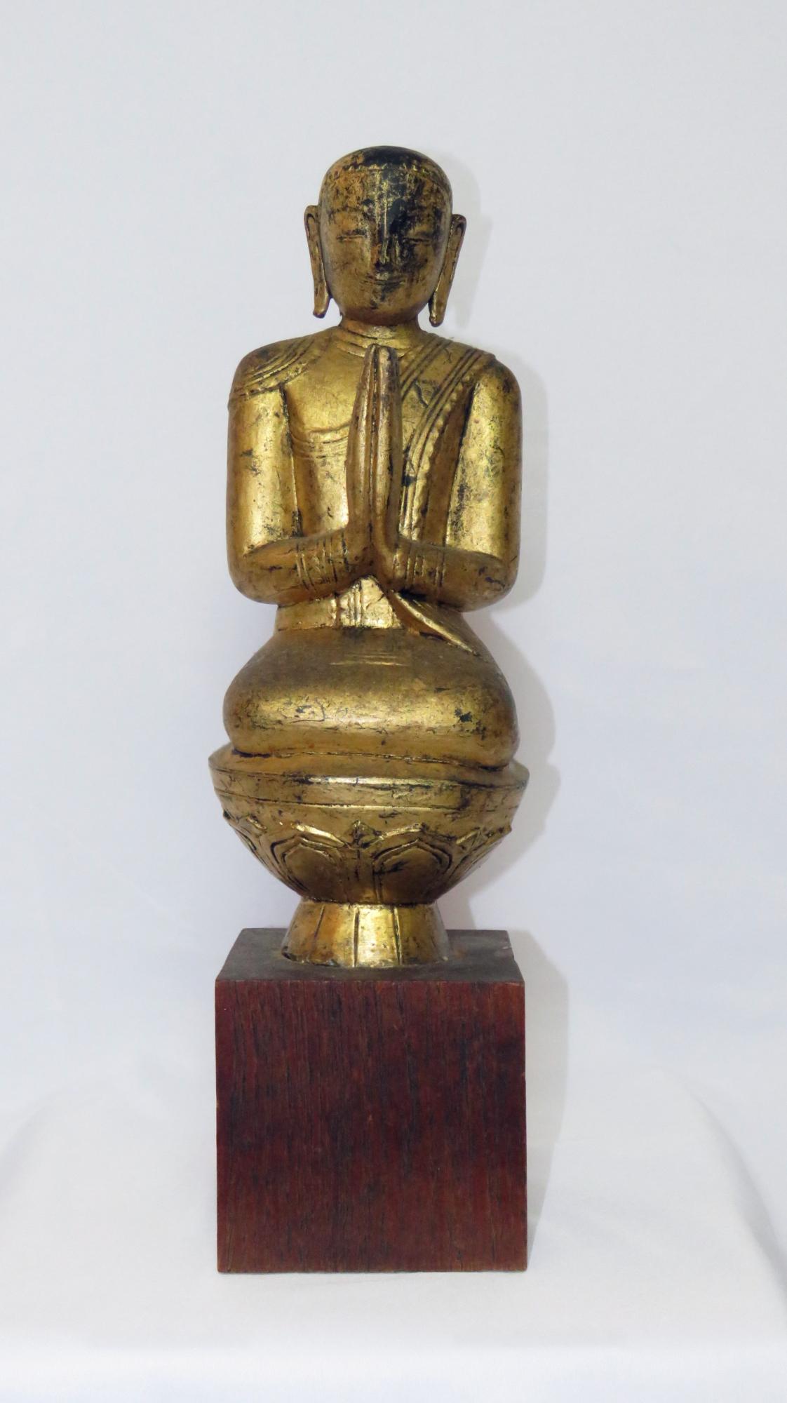 VINTAGE GILT PRAYING BUDDHA ON A TEAK MOUNT: Vintage carved and gilt praying form Buddha statue mounted on a teak wood base. The work is not visibly signed. unsigned Measures: Sculpture: 13 5/8" x 5", Base: 4 1/2" x 4 7/8" x 4 7/8", Overall: 16 