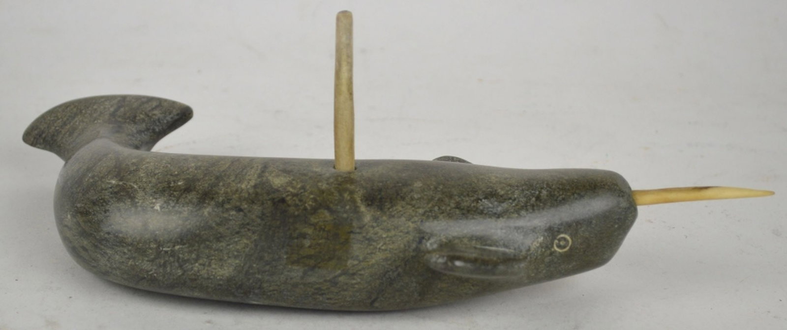 INUIT NARWAL SCULPTURE: A simple, yet elegant, carved stone sculpture of a narwhal. The work is not visibly signed. Note: Bottom peg appears to be for mounting. Measures: 4" x 11" x 6"