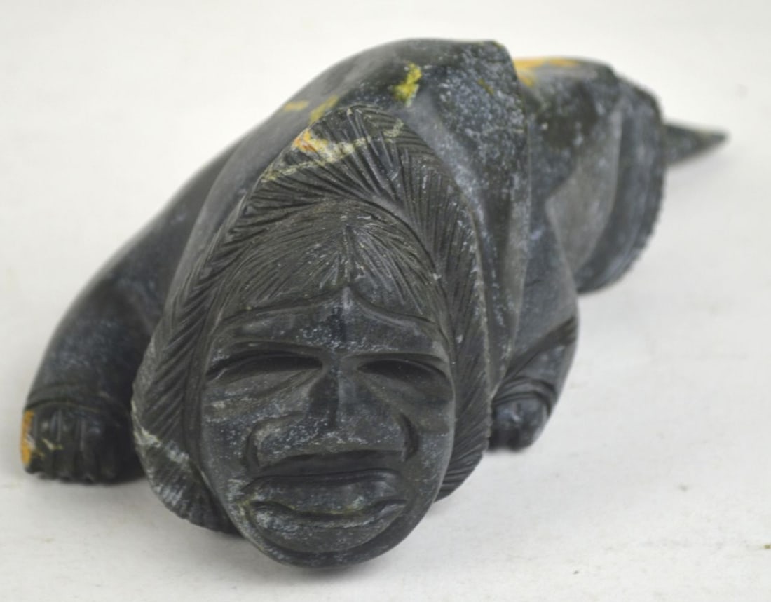 FINELY CARVED INUIT SEAL TRANFORMATIONAL SCULPTURE: A very appealing and finely carved Inuit stone sculpture. The work depicts the blending, or transformation, of an Inuk and seal or whale. The work is not signed / visibly marked. It has a drilled hole