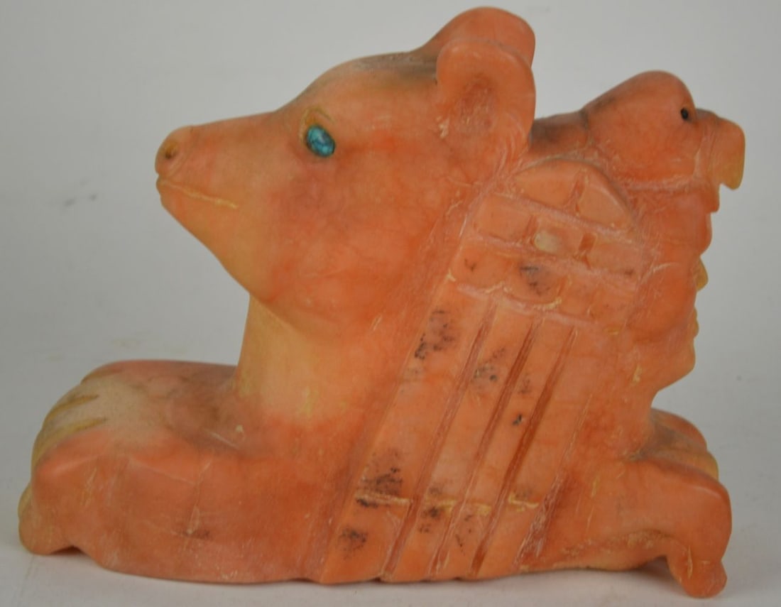 ZUNI CARVED STONE SCULPTURE: A Native American Zuni carved orange alabaster sculpture. The work depicts a face with an eagle above and a bear facing the other direction. It is quite the abstract surreal work. The bears
