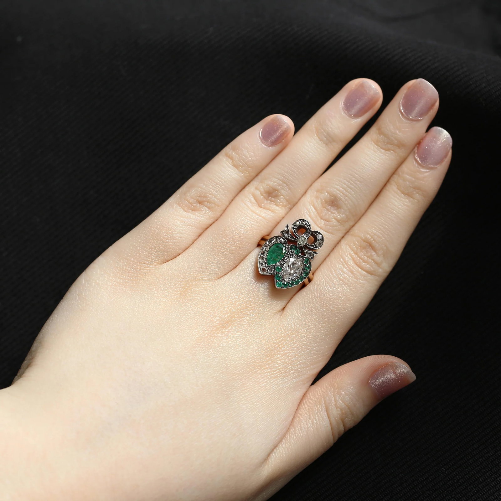 Victorian Emerald and Diamond Double Heart Ring: Here we have a delightful double heart ring taken from the Victorian era. This romantic antique piece features a striking combination of a pear-cut emerald and diamond, both set prominently at the cen