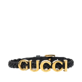 Gucci logo bracelet in black and gold plated leather for women.