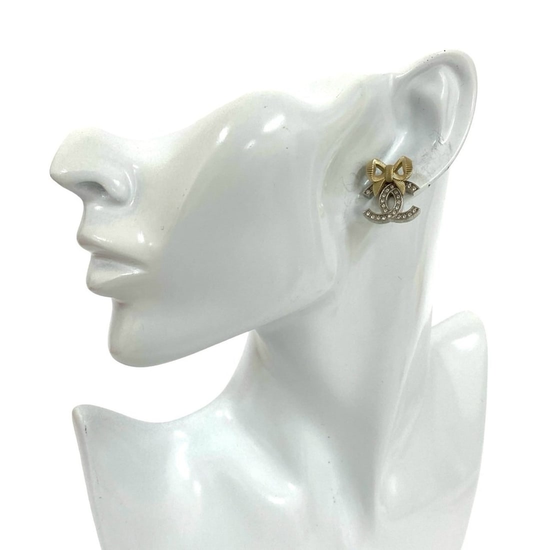 CHANEL Coco Mark Ribbon Motif GP Rhinestone Earrings in Silver and Gold (95251): --- Catalog ---Category: SizeSize (HxWxD): 20.00mm x 17.00mm / 0.79'' x 0.67''Category: DesignType: Stud earringsColor: Gold, SilverStone: RhinestoneGender: WomenMaterial: Gold platingCategory: Genera