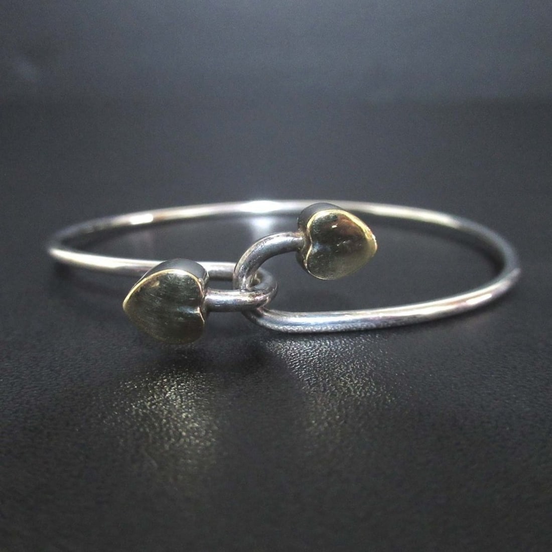 Tiffany & Co. Solid Double Heart Hook Bangle Bracelet, 925 x 750mm, Silver and Gold, Women's: --- Catalog ---Category: SizeLength: 17cm / 6.69''Weight: 8.7g / 0.3oz.Category: DesignType: Charm braceletColor: Gold, SilverGender: WomenMaterial: Gold (18K), Silver 925Category: GeneralLine: AppleB