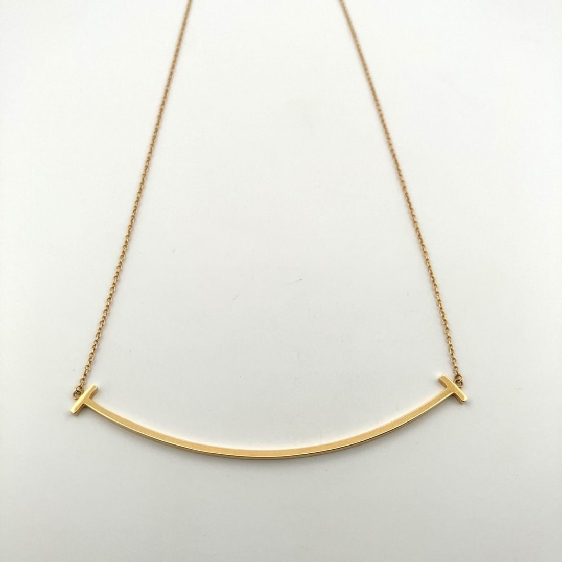 TIFFANY & CO. Tiffany T Smile Large Necklace in Au750 and K18YG (60011652): --- Catalog ---Category: SizeWeight: 3.7g / 0.13oz.Pendant Size: 6mm x 69mm / 0.23'' x 2.71''Neck Circumference: 46 cm / 18.11''Category: DesignColor: Yellow goldGender: WomenMaterial: Yellow gold