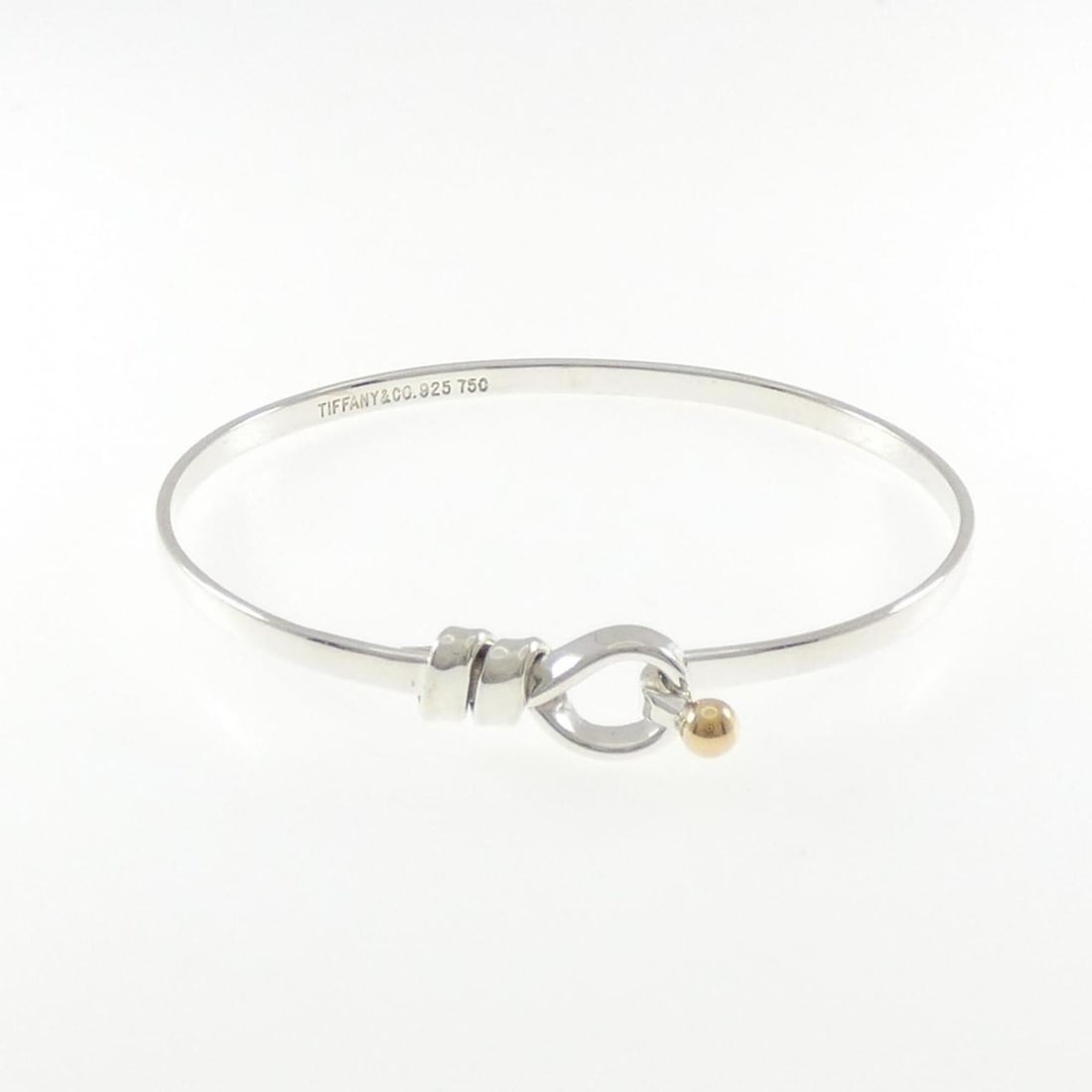 Tiffany Hook & Eye Bangle: --- Catalog ---Category: SizeLength: 17cm / 6.69''Category: DesignType: BangleColor: Gold, Yellow goldGender: WomenMaterial: Silver 925, Yellow gold (18K)Category: GeneralBrand: Tiffany--- Item List -