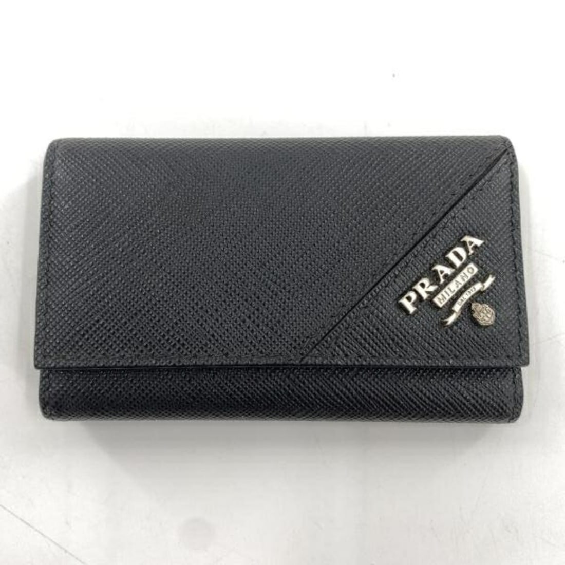 PRADA Key Case, 6 Hooks, Black Saffiano Leather: --- Catalog ---Category: DesignColor: Black, BlueMaterial: Saffiano triangle Category: GeneralBrand: PradaCountry of Origin: ItalyCategory: Physical PropertiesSize (HxWxD): 6.5cm x 10.5cm x 1.5cm / 2.