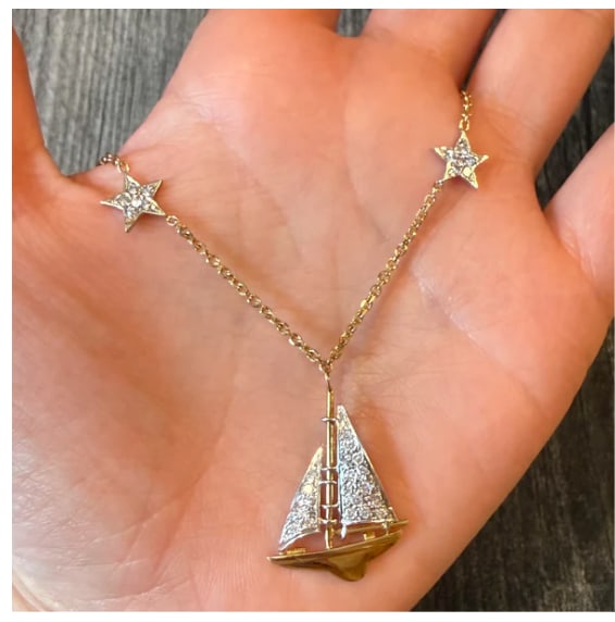 Diamond Sailboat and Star Necklace: Romantic celestial nautical theme assembly chain in 14K yellow gold. Displays an open-frame wirework sailboat silhouette pendant floating below an asymmetric pave-diamond starburst station charm (appr