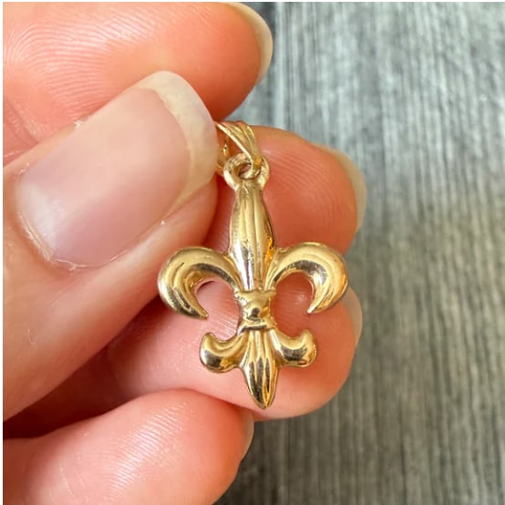Fleur De Lis Charm in 14K Gold: Regal heraldic lily pendant sharply cast in solid 14K yellow gold with fine milgrain detailing outlining the stylized petals. Dimensions: 18 mm x 13 mm. Weight: 2.1 grams.
