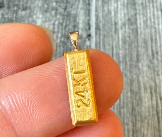 Mini 24K Gold Bar Charm: Novelty heavy bullion pendant designed as a mini stamped gold ingot bar showing fineness hallmarks "999.9 Fine Gold" on a matte frosted face inside a polished 14K outer frame housing. Dimensions: 15