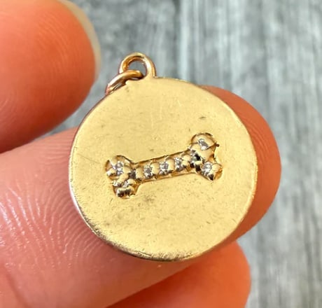 Diamond and 14K Gold Dog Bone Disc Charm: Polished circular disk pendant showcasing an applied central dog bone shape completely encrusted with micro pave-set white diamonds (approx. 0.06 ctw). Diameter: 14 mm. Weight: 1.6 grams.
