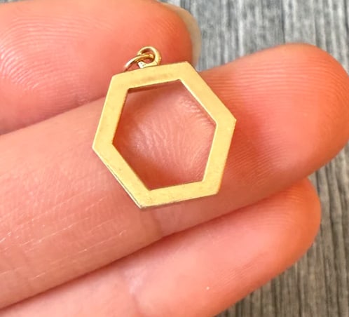 Open Hexagon Charm in 14K Gold: Minimalist contemporary geometric outline frame charm shaped into a sharp, six-sided hollow hexagon with polished flat wire edges. Dimensions: 15 mm x 13 mm. Weight: 0.9 grams.