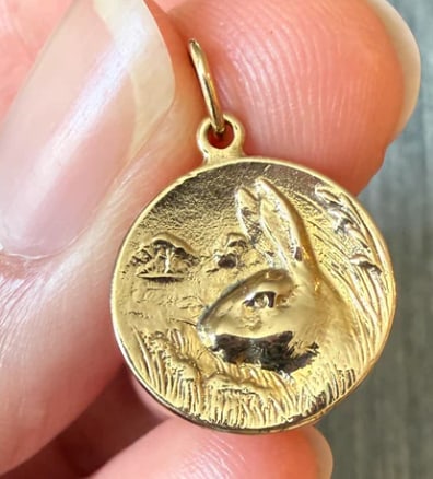 Small 14K Gold Charm of Rabbit or Bunny in the Field: Whimsical circular pictorial token featuring a textured 3D rabbit jumping through tall blades of engraved marsh grass field meadows. Diameter: 15 mm. Weight: 1.8 grams.