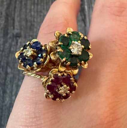 Set of Emerald, Sapphire, and Ruby Tulip Rings in 14K Gold: Set of three separate stackable interlocking bands, each hand-carved with a repeating tulip leaf cup pattern holding a central gemstone trio: one natural ruby, one sapphire, and one emerald cabochon (
