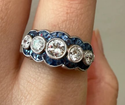 Art Deco Style 5 Stone Diamond Ring with Calibre Cut Sapphires (W): Low-profile geometric multi-stone ring set with a horizontal straight row of 5 bright Transitional-cut white diamonds (approx. 0.55 ctw), framed by a precise channel halo frame of custom calibre-cut
