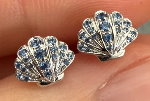 Sapphire and 18K White Gold Seashell Stud Earrings: Whimsical fan-shaped scallop seashell post earrings in 18K white gold, pave-set along the ridges with dark blue natural sapphires (approx. 0.45 ctw). Dimensions: 11 mm x 10 mm. Weight: 2.7 grams.