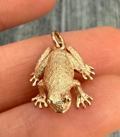 English 14K Gold Frog Charm: Heavy, solid-cast three-dimensional toad or frog figurine featuring realistic bumpy skin texturing and tiny inset green garnet or tourmaline gemstone eyes. Hallmarked London origin. Measures 16 mm lon