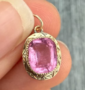 Victorian Pink Stone and 10K Gold Charm (S): Antique charm or small watch fob setting holding a fancy oval step-cut open-back pink tourmaline glass paste stone within a scalloped prong crown frame. Measures 12 mm x 10 mm. Weight: 1.4 grams.