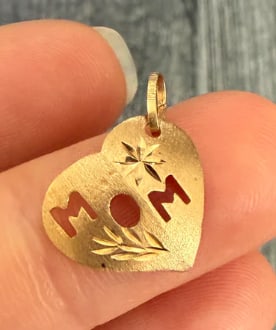 Vintage "MOM" Heart Charm In 14K Gold: Sweet puffed silhouette charm highlighting the word "MOM" rendered in bold cutout block letters directly across the center of a polished open ring heart framework. Dimensions: 15 mm x 14 mm. Weight: 1