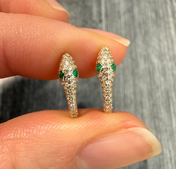 Diamond Pave and Emerald Snake Huggie Earrings: 14K gold huggie earrings featuring a diamond pave snake with emerald eyes.