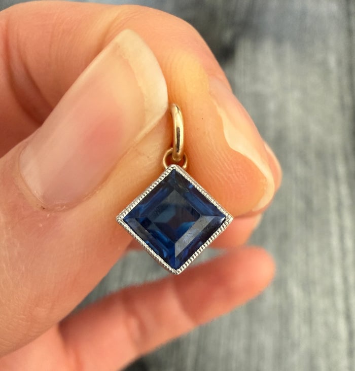 Art Deco Natural Sapphire and 14K Gold Square Cut Solitaire Charm: A vintage 14K gold charm featuring a square-cut natural sapphire.
