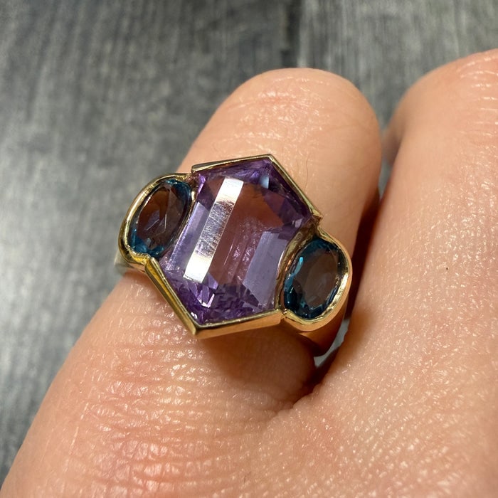 Geometric Amethyst and Blue Topaz Cocktail Ring: A bold 14K gold statement ring featuring a geometric arrangement of amethyst and blue topaz gemstones.