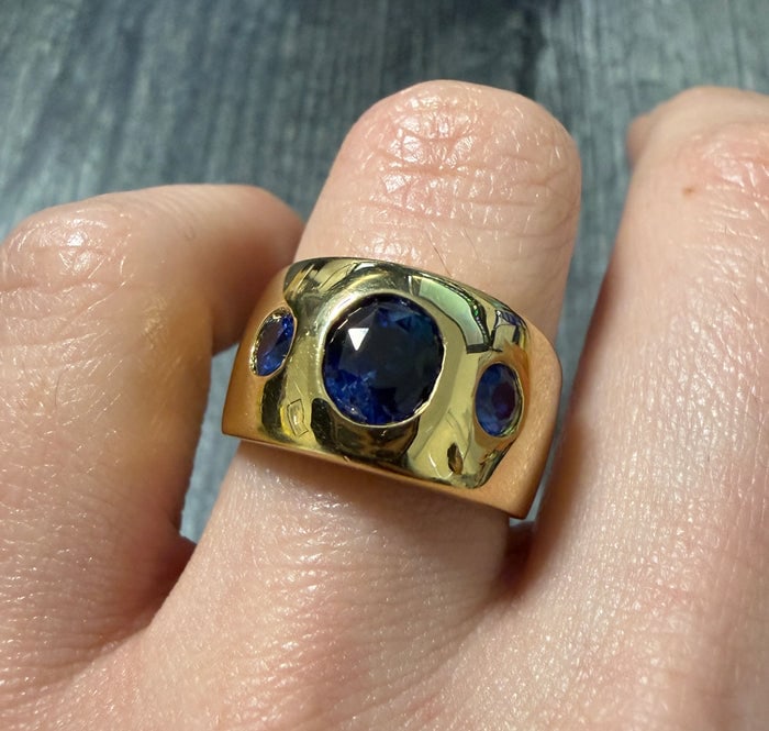 Flush Set Triple Sapphire Wide Band in 18K Gold: A heavy 18K yellow gold wide band featuring three vibrant blue sapphires flush-set into the metal.