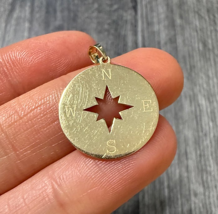 North Star Compass Charm in 14K Gold: A 14K gold circular charm featuring an embossed North Star compass rose, symbolizing guidance.