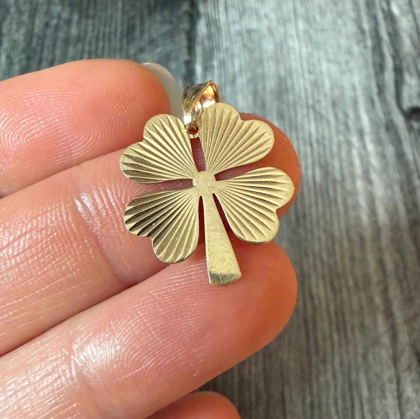 Engine Turned Four Leaf Clover Charm in 14K Gold: Metal: 14K Yellow GoldWeight: 1.2 gramsMeasurement: 0.8 inches long by 0.75 inches wideCondition: In good condition with some minor surface wearFollow us on Instagram @alphaomegajewelry for the latest