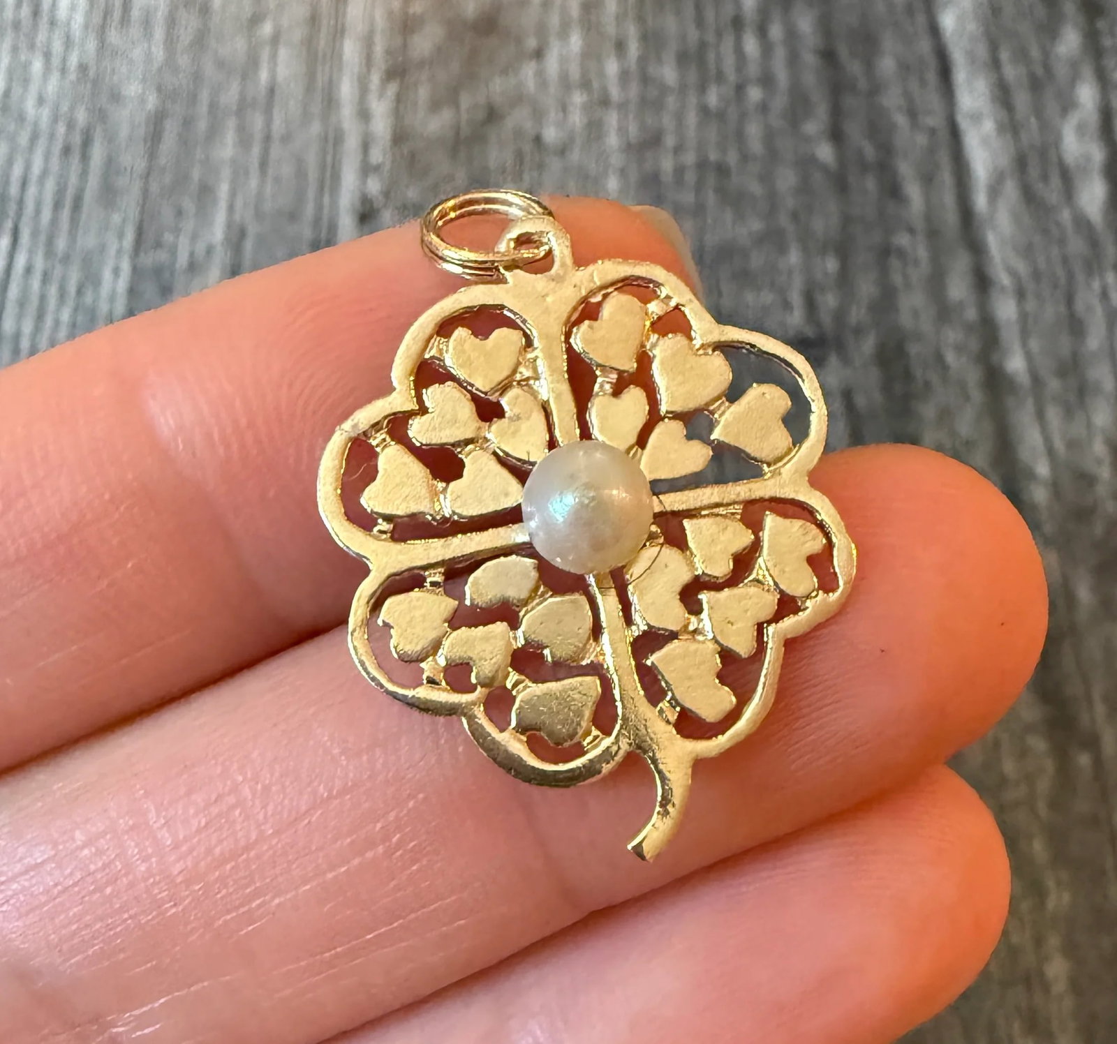 Vintage Clover Charm Filled with Hearts: Metal: 14K Yellow Gold Weight: 2.6 gramsMeasurements: 1.1 inches long by 0.8 inches wideMarkings: "14K"Condition: In good condition with some abrasions on the pearl and some minor surface wear Follow