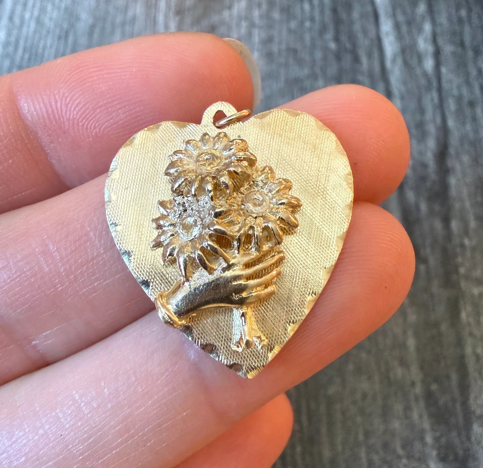 Vintage Hand Holding Bouquet Heart Charm in 14K Gold: Metal: 14K Yellow GoldWeight: 4 gramsMeasurements: 1.1 inches long by 1 inch wideMarkings: "M&M 14K"Condition: In very good condition with some minor surface wear .Follow us on Instagram
