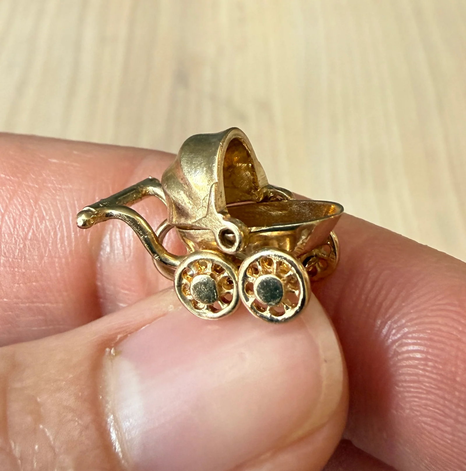 Vintage Articulated Baby Carriage or Pram Charm in 14K Gold: An articulated baby carriage or pram charm with spinning wheels and a hood that slides back and forth. Metal: 14K Yellow GoldWeight: 3.3 gramsMeasurements: 0.5" long by 0.75" wideMarkings: "14K"
