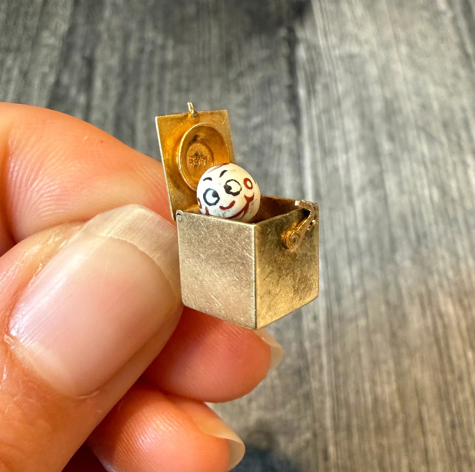 Articulated Enamel Jack in the Box Charm in 14K Gold: Metal: 14K Yellow Gold Weight: 3.2 gramsMeasurements: 0.4 inches long by 0.4 inches wideMarkings: "14K"Condition: In good condition with some enamel loss on the top of Jack's head as well as some surf