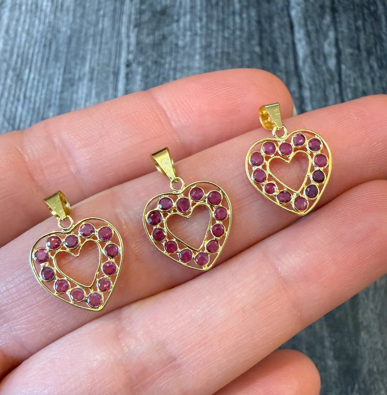 Ruby and 18K Gold Open Heart Charm (3): Metal: 18K Yellow Gold Weight: 0.6 gramsRubies: Approximately 0.36 caratsMeasurements: 0.5 inches long by 0.5 inches wideMarkings: "18K"Condition: In good condition with some minor surface wear Follow