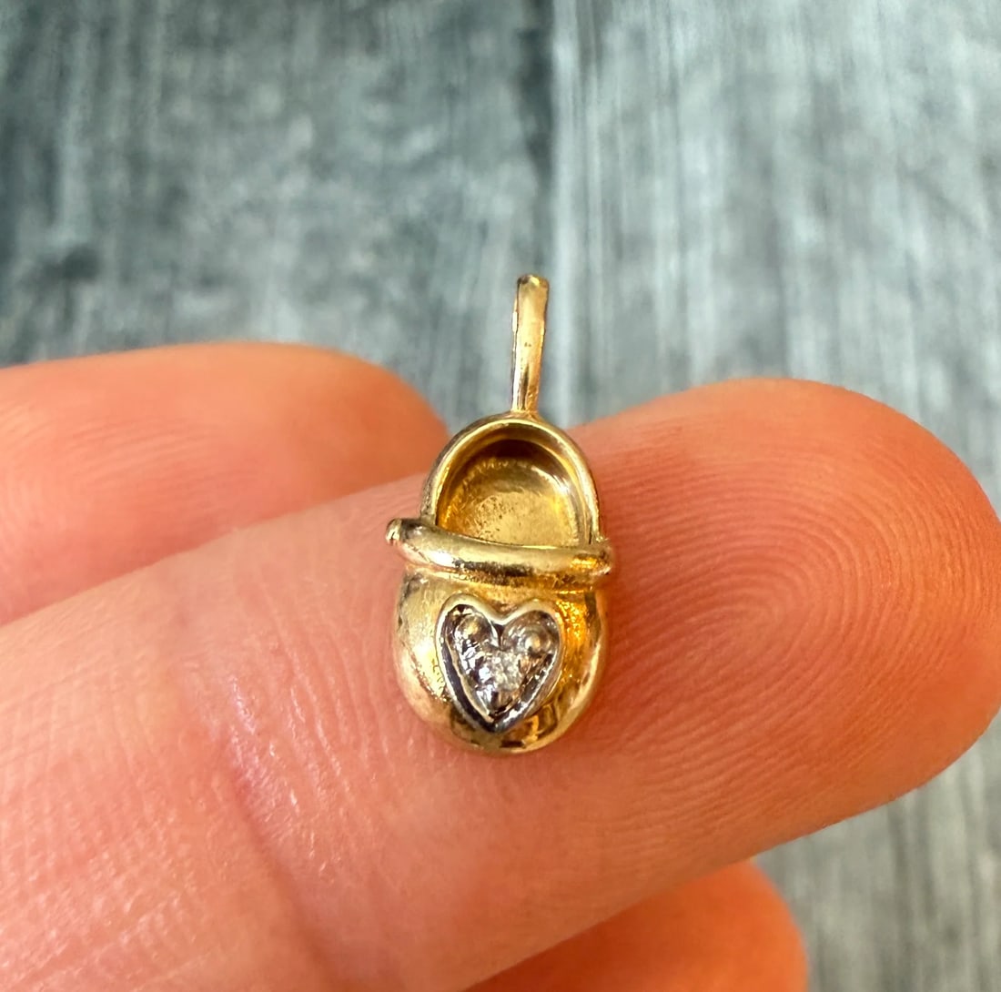 Mini Diamond Baby Shoe Charm in 14K Gold: Metal: 14K Yellow and White Gold Weight: 0.8 gramsMeasurements: 0.35 inches long by 0.25 inches wideCondition: In very good condition with some minor surface wear Follow us on Instagram @alphaomegajew