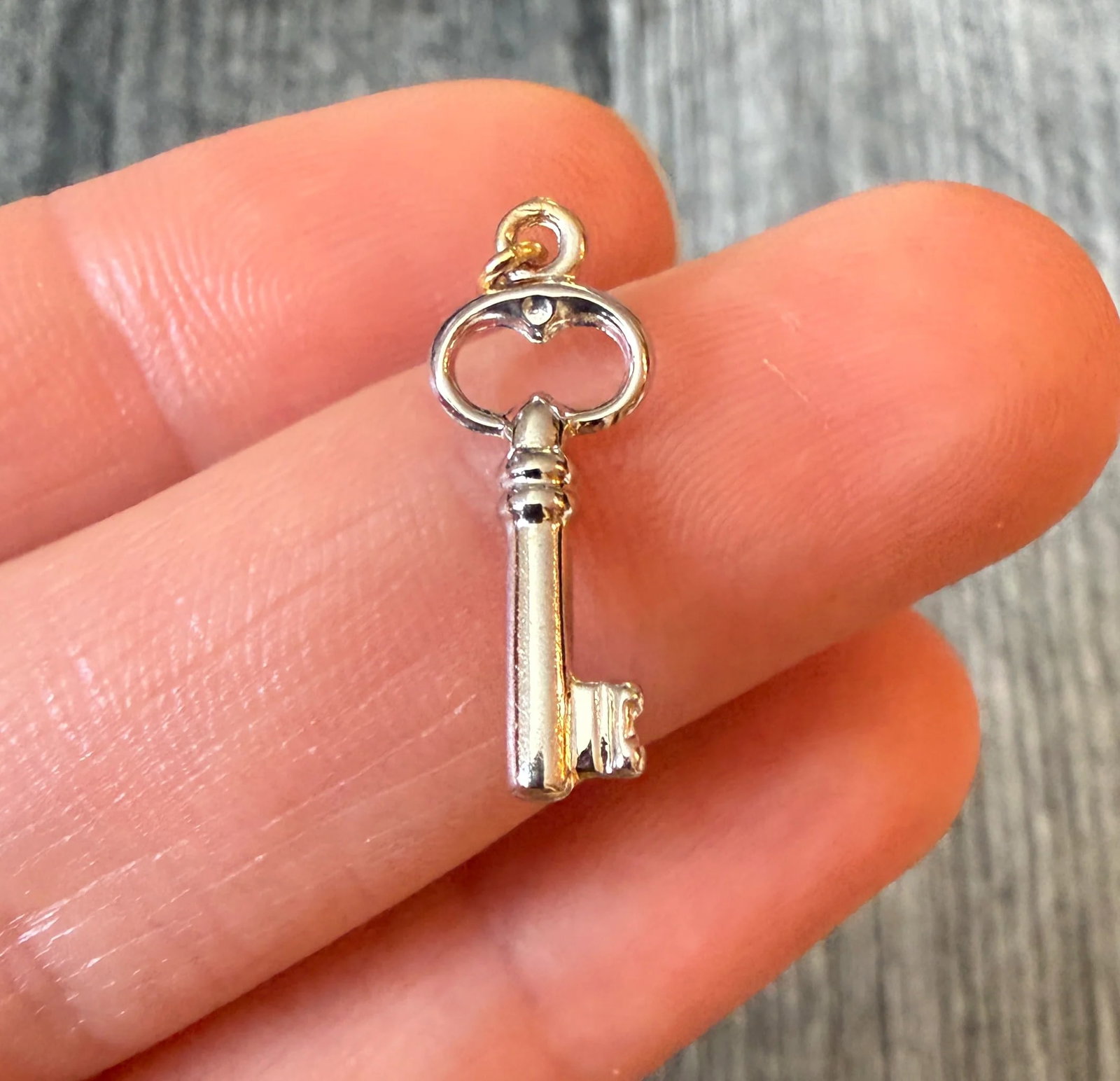 Small Puffy Skeleton Key Charm in 18K White Gold: Metal: 18K White Gold (acid tested)Weight: 0.4 gramsMeasurements: 0.7 inches long by 0.3 inches wideMarkings: NoneCondition: In very good condition with some minor surface wear. We can add a larger si