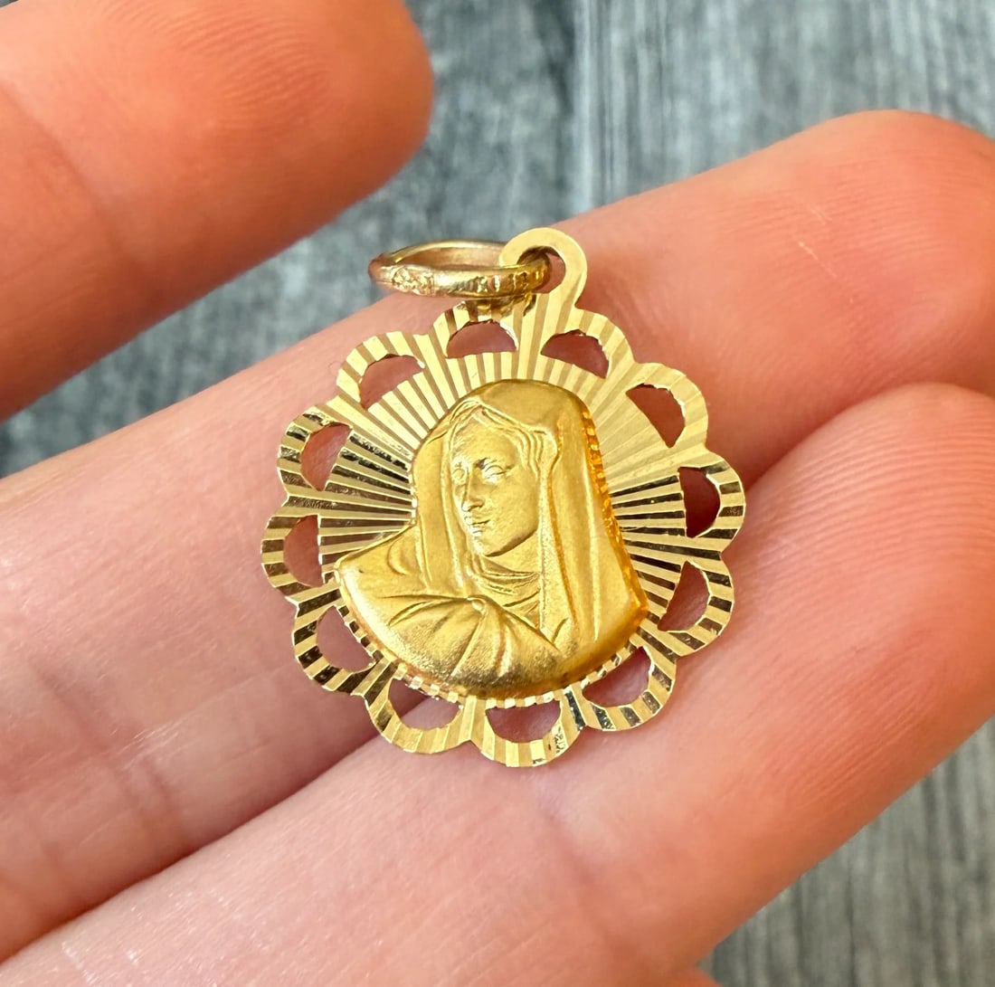 Radiant Reversible Virgin Mary and Jesus Charm in 14K Gold: Metal: 14K Yellow Gold Weight: 2.2 gramsMeasurements: 0.75 inch diameter Markings: "KT 14 ITALY"Condition: In very good condition with some minor surface wear Follow us on Instagram @alphaomegajewelry