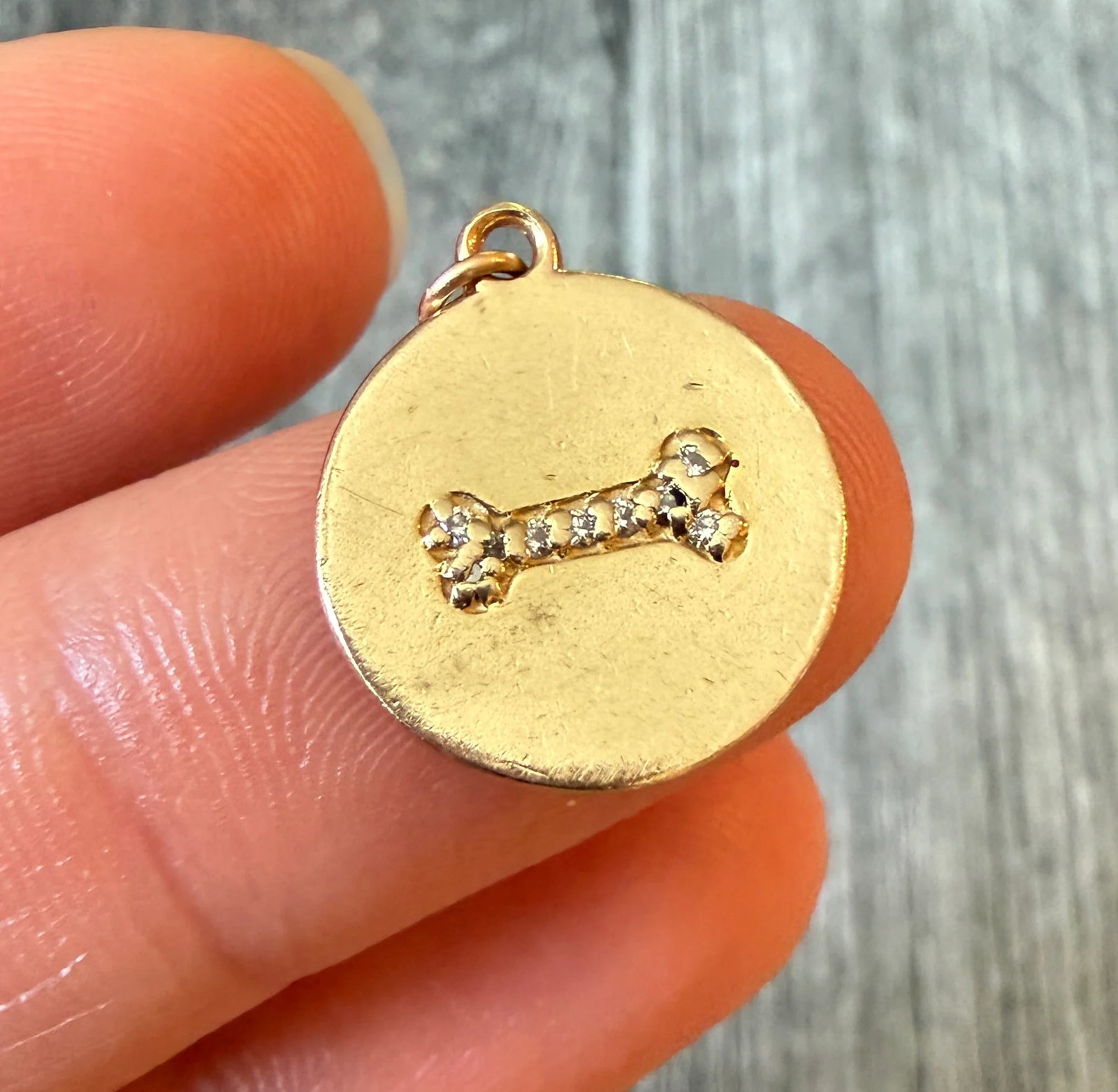 Diamond and 14K Gold Dog Bone Disc Charm: Metal: 14K Yellow Gold Weight: 2.7 gramsDiamonds: Approximately 0.03 caratsMeasurements: 0.65 inch diameter Condition: In fair condition with some nicks on the edges of the gold and some surface wear.
