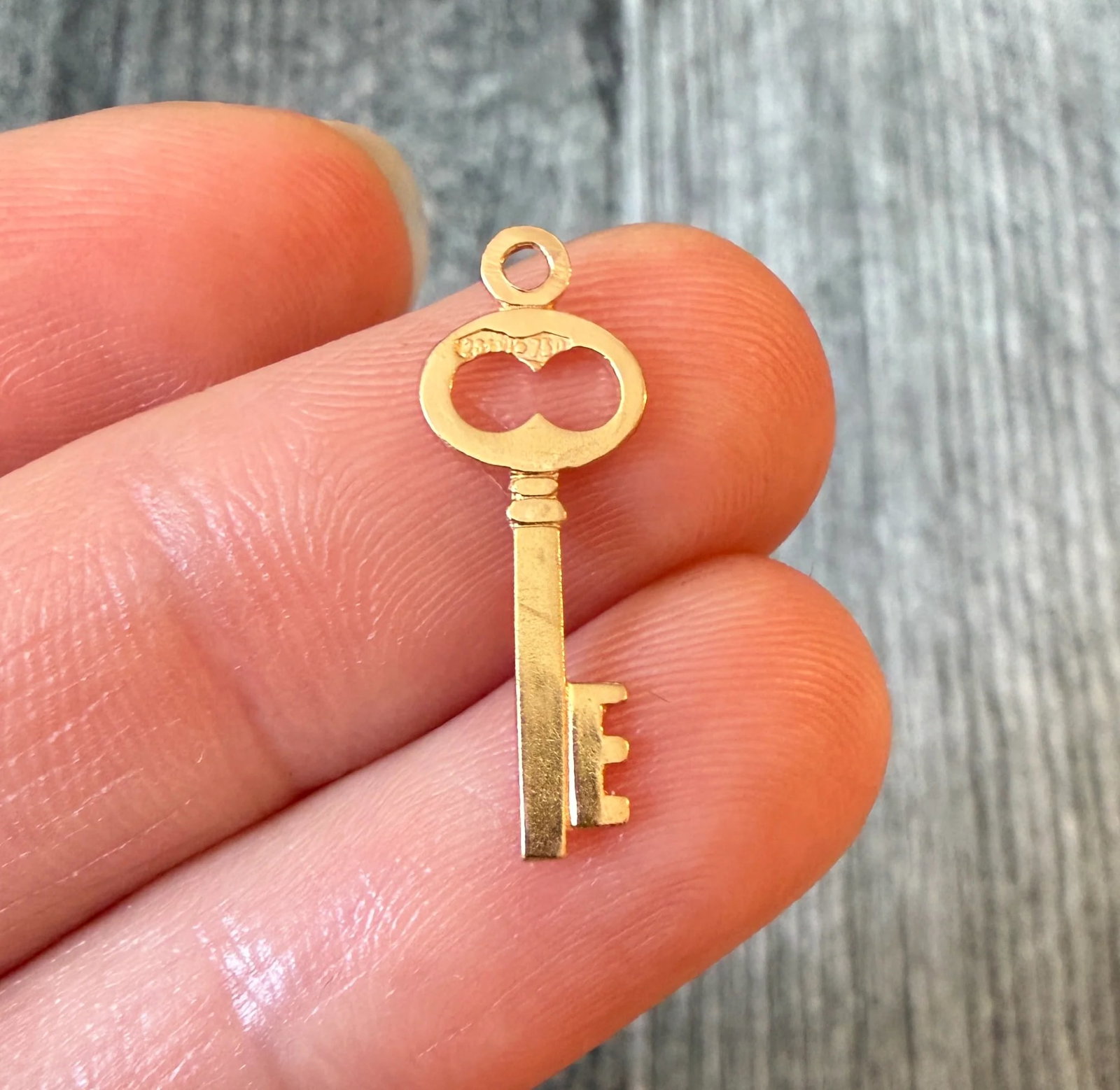 Skeleton Key Charm in 18K Gold: Metal: 18K Gold Weight: 0.5 gramsMeasurements: 0.75 inches long by 0.3 inches wideMarkings: "750"Condition: In very good condition with some minor surface wear. We can add a bale prior to shipping if 