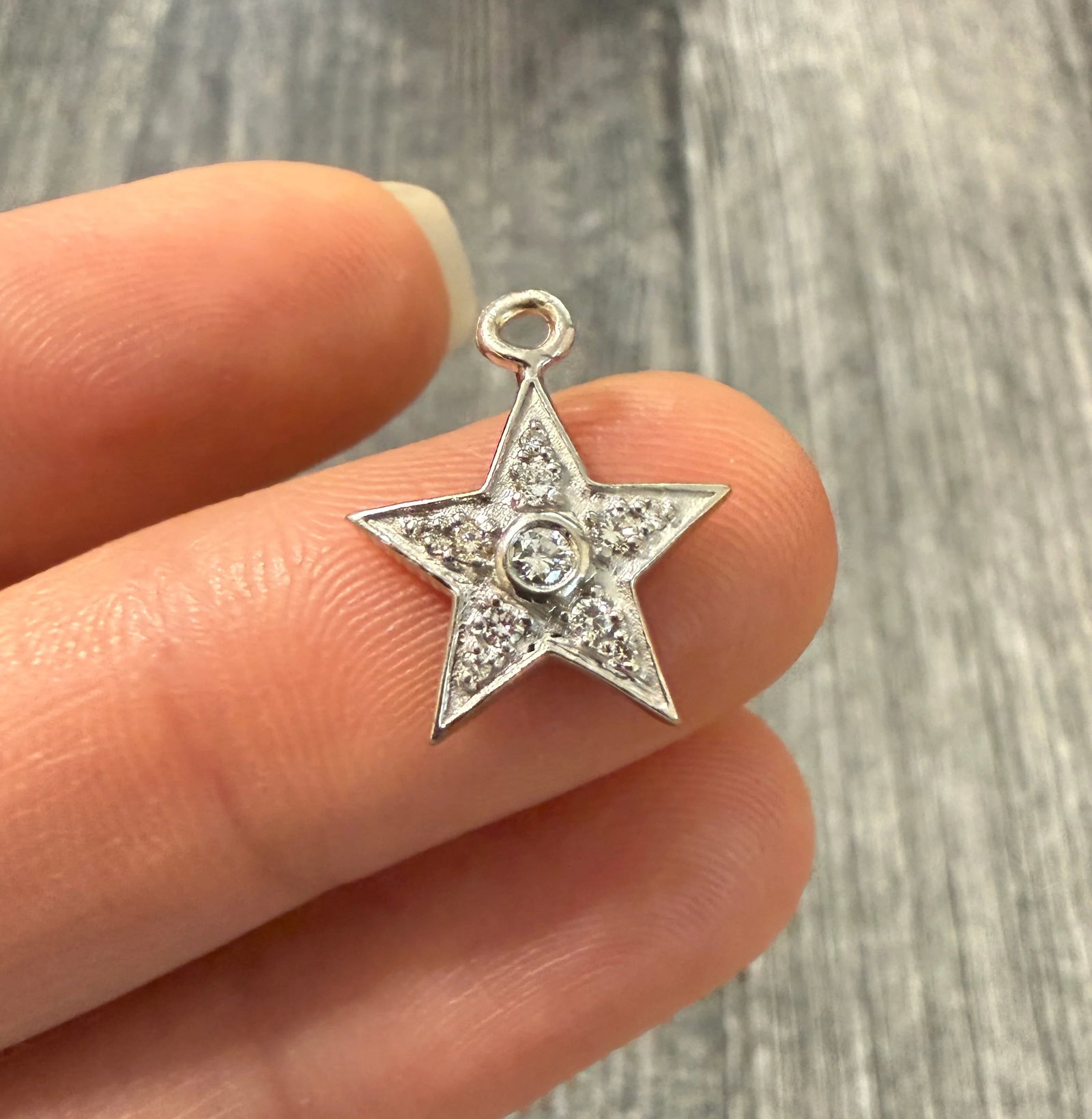 Diamond and 18K White Gold Star Charm: Metal: 18K White GoldWeight: 1.7 gramsDiamonds: Approximately 0.15 caratsMeasurements: 0.5 inches long by 0.55 inches wideMarkings: "18K"Condition: In good condition with some minor surface wear. We