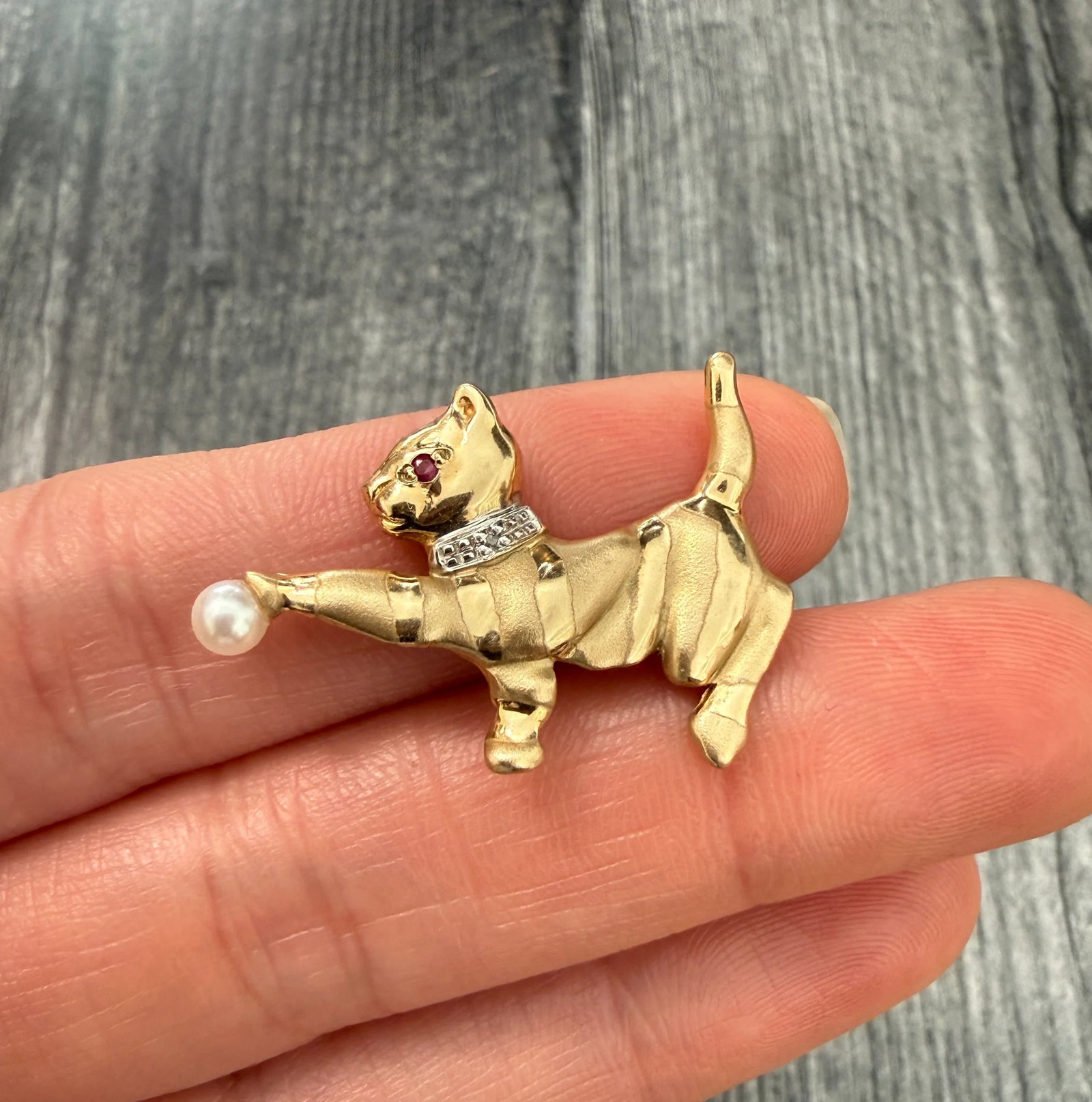 Playful Cat Pin in 14K Gold with Pearl Ball: Metal: 14K Yellow Gold Weight: 3.6 gramsMeasurements: 0.9 inches long by 1.5 inches wideMarkings: "JED 14K"Condition: In good condition with some minor surface wear.Follow us on Instagram @alphaomegaj