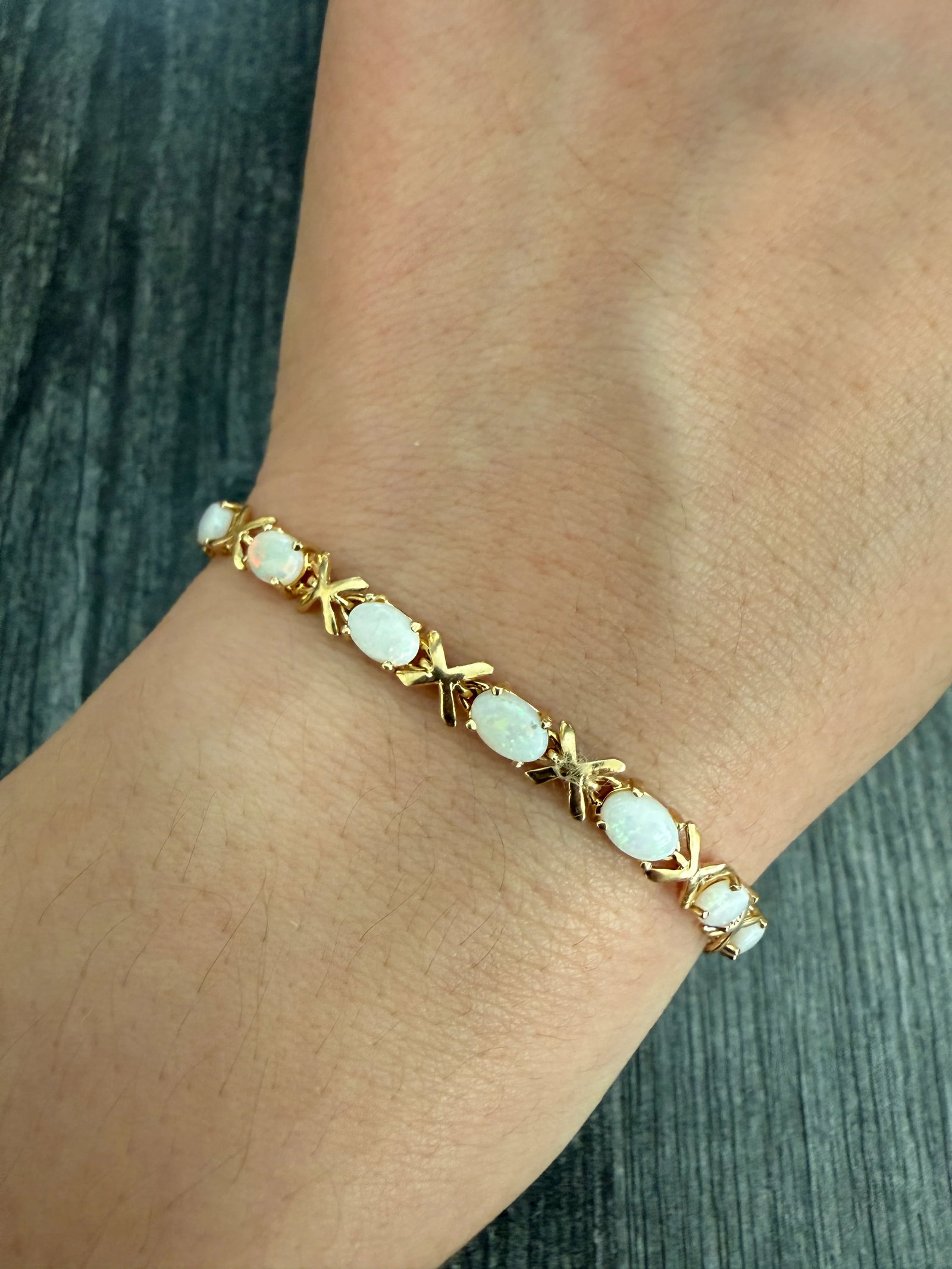 Opal and 14K Gold XOXO Line Bracelet: Metal: 14K Yellow Gold Weight: 7.4 gramsOpals: Approx 6 mm long by 4.2 mm wide each Measurements: 7 inches long by 5.1 mm wideMarkings: "14K"Condition: In good condition with some minor surface wear F